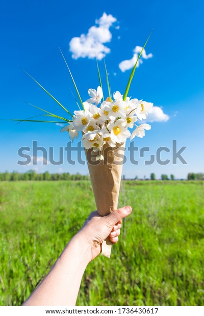 White flowers in hand\
against the sky with clouds. The concept of summer and joy.\
conceptual realism.