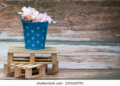 White Flowers Inside A Blue Metal Bucket With White Polka Dots On A Wooden Pallet. Wild Flowers. Home Decor.