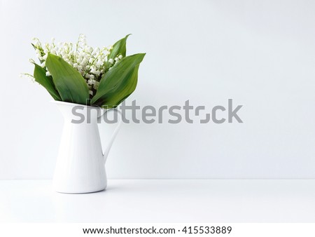 White flowers in a jar on the white background. Styled photo. Lilly-of-the-valley photo.