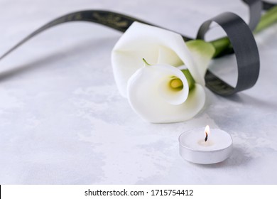 White Flowers With A Mourning Ribbon On A Concrete Background. Copy Space. Death Concept