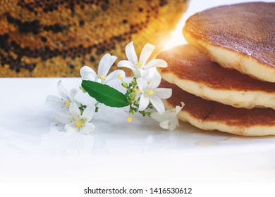 White flowers or Orange jasmine with stack of pancakes on white background, honeycomb in background