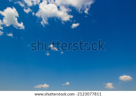 White fluffy clouds and bright sun on dark blue sky.