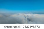 White fluffy clouds float above the mountaintops, forming a sea of ​​clouds. The blue sky in the morning, the sunlight shining on the fluffy clouds, it