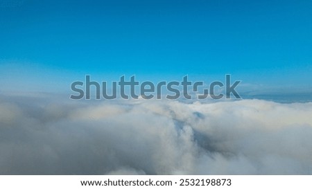 White fluffy clouds float above the mountaintops, forming a sea of ​​clouds. The blue sky in the morning, the sunlight shining on the fluffy clouds, it's like floating in heaven. wonderful nature