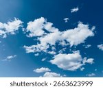 White fluffy clouds float gracefully against a brilliant blue sky on a sunny day.