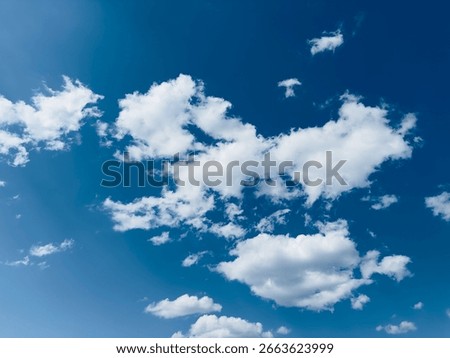 White fluffy clouds float gracefully against a brilliant blue sky on a sunny day.