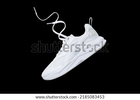 White flying sneakers isolated on black background