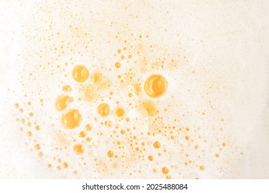 White Foam Beer With Small Bubbles Texture And Yellow Water. Top View