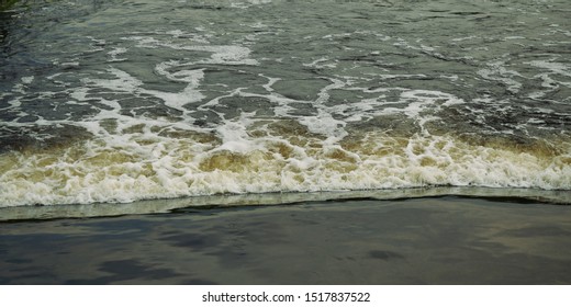 White Foam Bubbles Moving On The Brown Water Surface In The Wastewater Treatment Pond