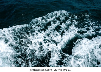White foam in the sea from a sailboat.Blue water of different shades in the ocean mixed with white foam in Buracona the blue eye cave.Deep Blue Ominous Ocean Water abstract Background Image.