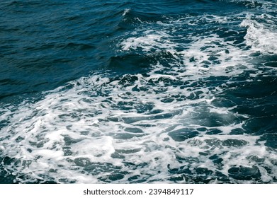 White foam in the sea from a sailboat.Blue water of different shades in the ocean mixed with white foam in Buracona the blue eye cave.Deep Blue Ominous Ocean Water abstract Background Image.