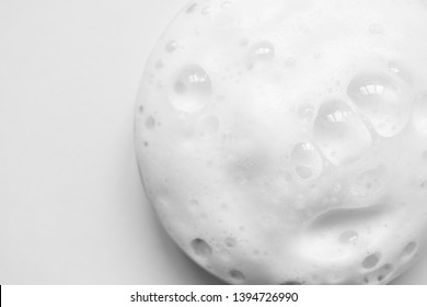 White foam texture from soap, shampoo or cleanser on white background. Close up, macro