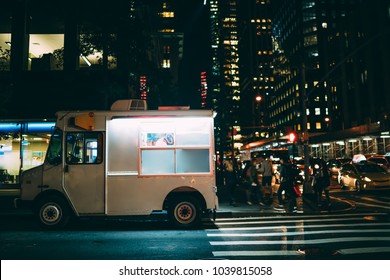 White Food Truck Parked On City Street Near Buildings Using For Retail Business Startup, Van Automobile With Mock Up Copy Space Area For Brand Name Selling Ice Cream Parked In Urban Setting At Night