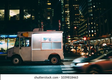 White Food Truck Parked On City Street Near Buildings Using For Retail Business Startup, Van Automobile With Mock Up Copy Space Area For Brand Name Selling Ice Cream Parked In Downtown At Night