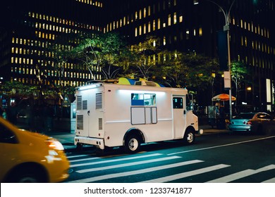 White Food Truck Parked On City Street Near Buildings Using For Retail Business Startup, Van Automobile With Mock Up Copy Space Area For Brand Name Selling Ice Cream Parked In Urban Setting At Night