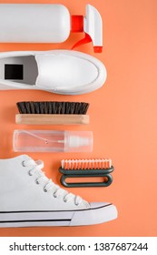 White Footwear, Brushes And Cleanser Sprays On Orange Background, Top View. Proper Cleaning And Care For Your Shoes.