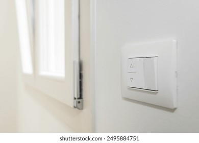 White frame and buttons of the roller shutter switch up and down on white wall in the house