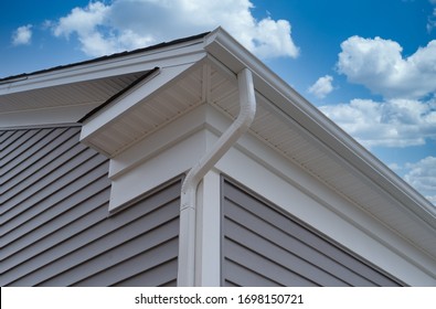 White Frame Gutter Guard System, With Gray Horizontal Vinyl Siding Fascia, Drip Edge, Soffit, On A Pitched Roof Attic At A Luxury American Single Family Home Neighborhood USA
