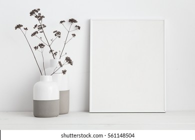  white frame mock up and dry twigs in vase on book shelf or desk. White colors.
