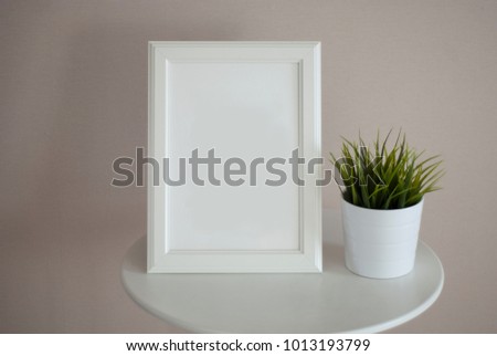 The white frame mock up on the white table and plants