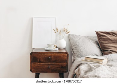 White frame mockup on retro wooden bedside table. Modern white ceramic vase with dry Lagurus ovatus grass and cup of coffee. Beige linen and velvet pillows in bedroom, Scandinavian interior. - Shutterstock ID 1788750317