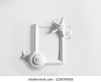 White frame mockup with seashells on white wall background. Template photo frame for text. Poster mockup.