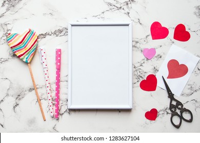 White Frame Mockup And Valentines Day Decorations On Marble Table