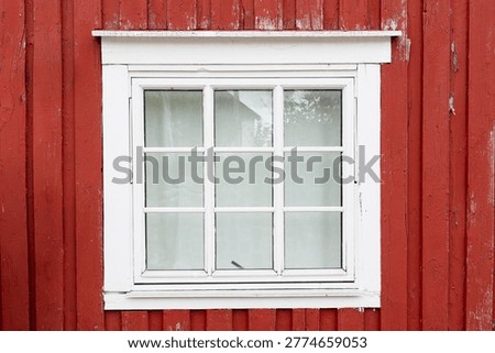 White framed window on a red wooden wall, typical of Nordic rural architecture.