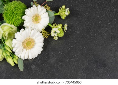 White Fresh Flowers On Granite Tombstone Background. Funeral And Condolences Theme.