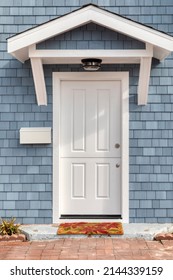 White front door with blue shingle siding of single family home 