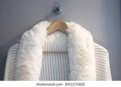 White fur coat hanging on the clothes hanger, closeup of photo
