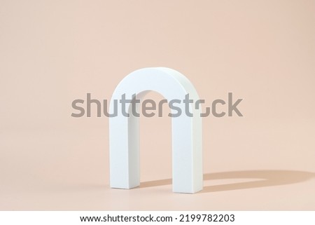 A white geometric shape in the form of the arch standing on a beige background
