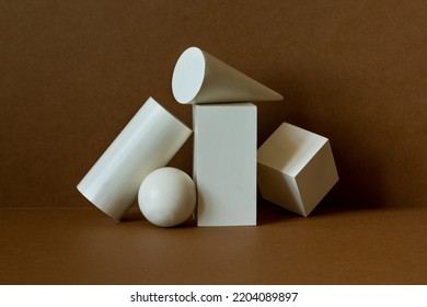 White geometric shapes on a brown background. Platonic figures cube rectangle sphere prism, pyramid arranged in an abstract still life composition - Shutterstock ID 2204089897