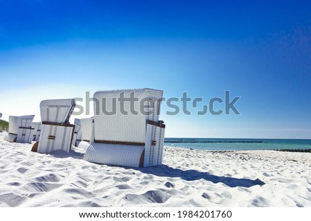 White German Strandkörbe or roofed whicker beach chairs on an empty beach at Ahrenshoop on the Fischland-Darß-Zingst peninsula, Germany.