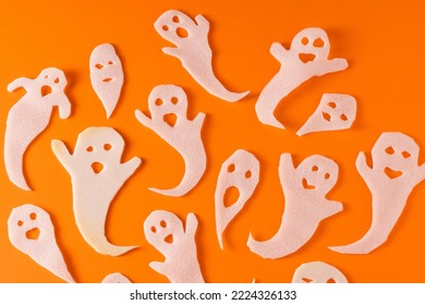 White ghosts kids craft for Halloween. Wrapping paper ghost on orange background top view. A scary and funny monster toy with your own hands. Cartoon creepy Whisper. DIY hand made. Set boo characters