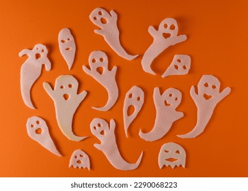 White ghosts kids craft for Halloween. Wrapping paper ghost on orange background top view. A scary and funny monster toy with your own hands. Cartoon creepy Whisper. DIY hand made. Set boo characters