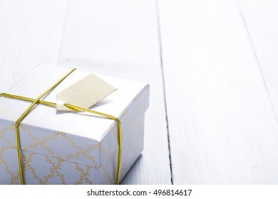 white gift box with golden string and card on bright wood table - Shutterstock ID 496814617