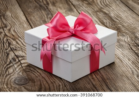 White gift box with a pink ribbon on the old board.