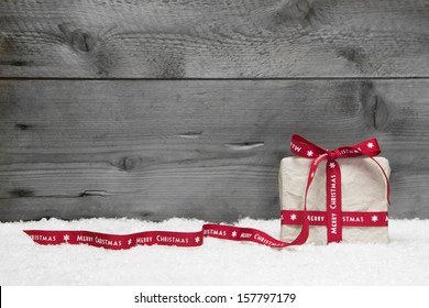 White Gift Box With Red Long Ribbon And Bow On Grey Wooden Background