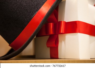 White Gift Box Tied With Elegant Red Ribbon And Black Hat. Shoot From Close Up, Waiting For The Festival Day At The End Of The Year And Can Used In Various Festivals.