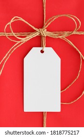 White Gift Tag Mockup On A Red Christmas Gift.