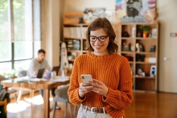 White Ginger Woman In Eyeglasses Using Cellphone While Working At Office Indoors