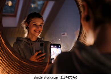 White Girl Taking Selfie On Mobile Phone While Looking In Mirror At Home