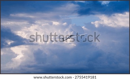 White glider plane soaring through a vibrant blue sky with soft white clouds, captured during a peaceful recreational flight on a bright sunny day.