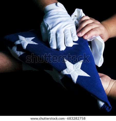 A white gloved hand presents a flag to a woman's hands