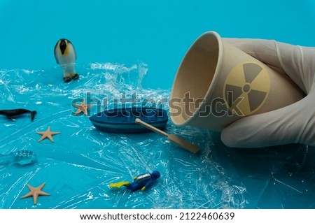 White gloved hands hold Paper Cup with nuclear radiation warning symbols and pour water into sea. Nuclear waste water. Pollutant discharge. Ecological damage. Chemical contamination.Environmental
