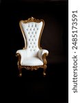 A white and gold throne chair on a black background with no one sitting in it