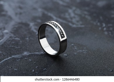 White Gold Wedding Ring With Black Gemstones On Black Background. Fashion Mens Jewellery