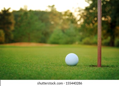 White Golf Ball On Putting Green With Bunker In Background