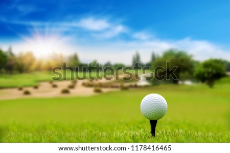White Golf ball on tee ready to be shot on blurred beautiful landscape of golf course in bright day time with copy space. Sport, Recreation, Relax in holiday concept.